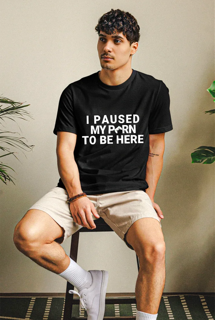 Man wearing a black t-shirt with humorous text, sitting on a chair.
